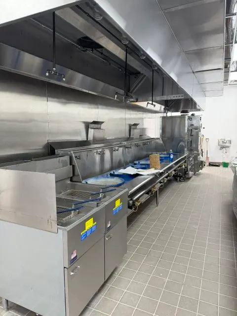 Stainless steel commercial kitchen equipment and plumbing install with polished floor