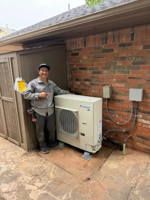 Technician pointing to a newly installed Daikin outdoor unit on a residential patio